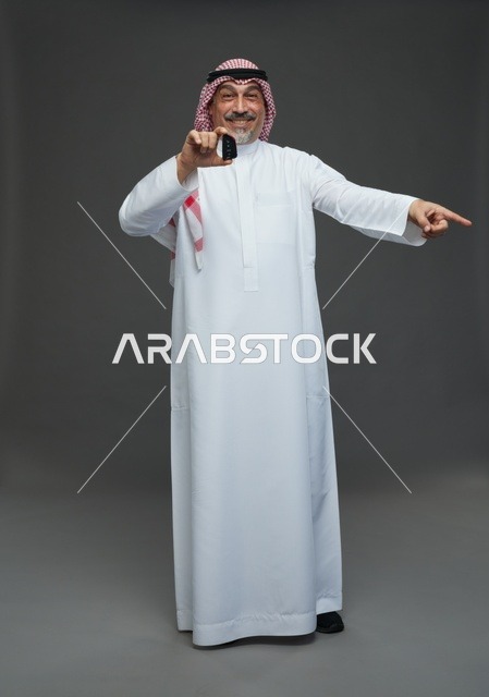 رجل سعودي يحمل مفتاح سيارة ويبتسم