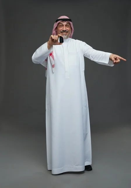 رجل سعودي يحمل مفتاح سيارة ويبتسم
