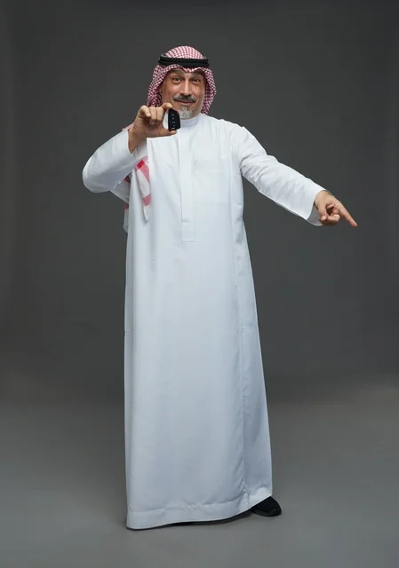 Saudi Man Holding Car Key Pointing on Grey Background