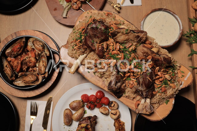 مائدة طعام مكونة من طبق اللحم والارز المزين بالمكسرات ، طبق المحار اللذيذ ، تناول طعام الغداء ، وجبة غذائية ، الافطار الرمضاني ، ماكولات عربية 