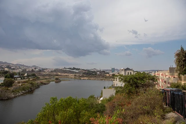 Urban Lake and Cityscape Under Cloudy Sky