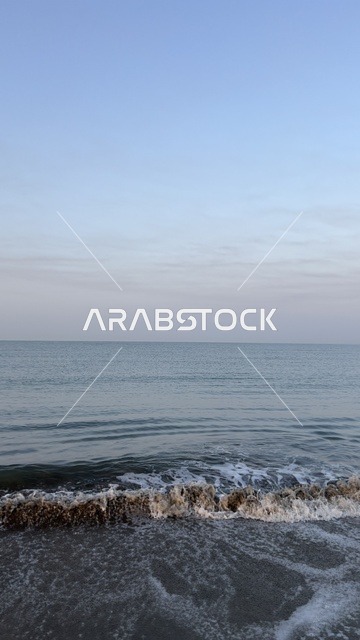 أمواج البحر تتكسر على الشاطئ الرملي وقت الغسق