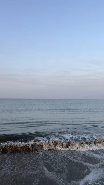 أمواج البحر تتكسر على الشاطئ الرملي وقت الغسق