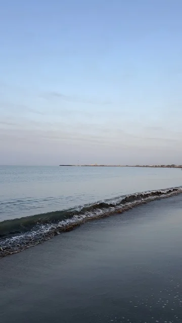 Small Ocean Waves on Dark Sandy Beach During Sunrise