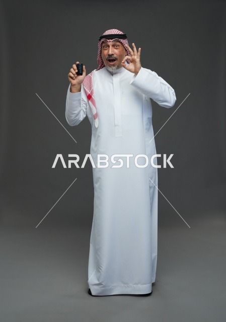 رجل سعودي يحمل مفتاح سيارة مع إيماءة موافق