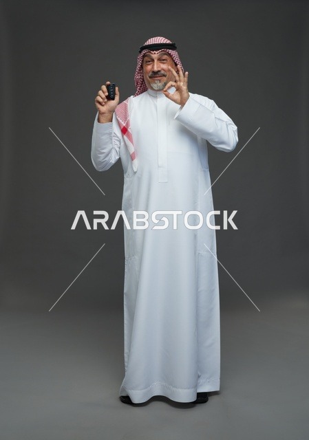 رجل سعودي بالثوب يحمل مفتاح سيارة مع علامة التمام