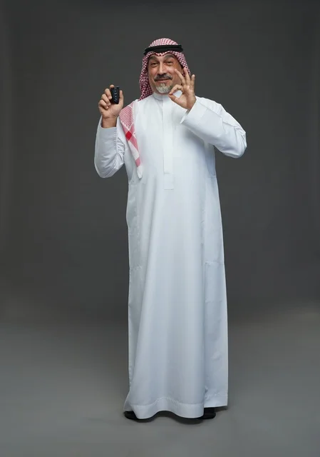 رجل سعودي بالثوب يحمل مفتاح سيارة مع علامة التمام