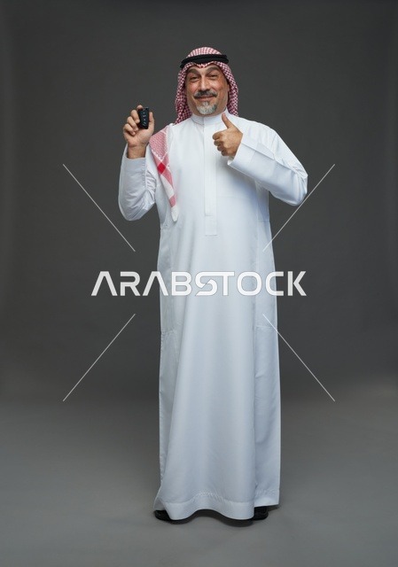رجل سعودي يمسك مفتاح سيارة مع إيماءة الإبهام