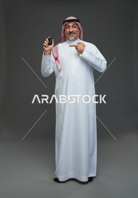رجل سعودي يحمل مفتاح سيارة في استوديو تصوير