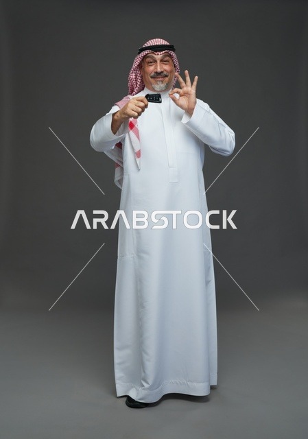 رجل سعودي يحمل بطاقة ائتمانية ويشير بعلامة التمام