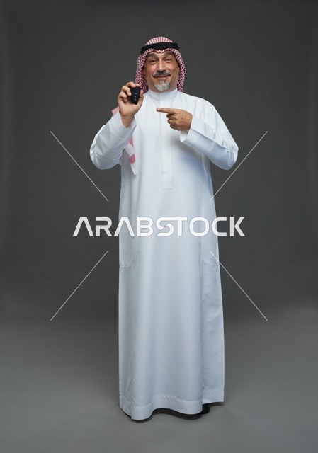 رجل سعودي يحمل مفتاح سيارة في الاستوديو