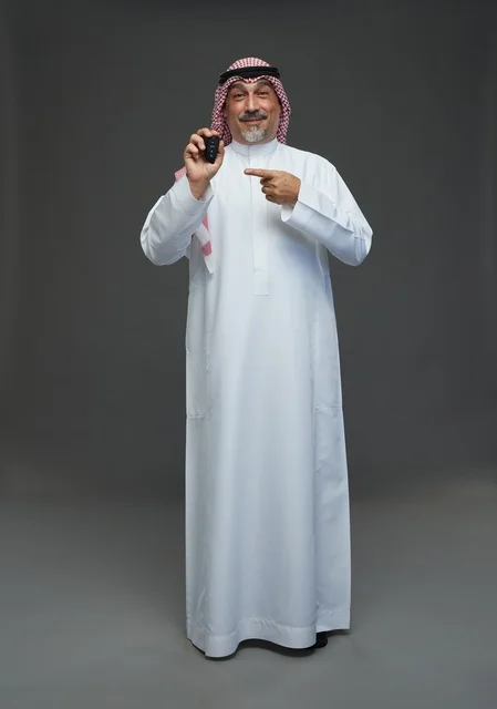 رجل سعودي يحمل مفتاح سيارة في الاستوديو