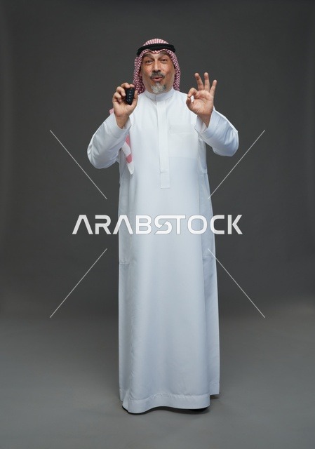 Saudi Man Holding Car Key with Okay Gesture in Studio