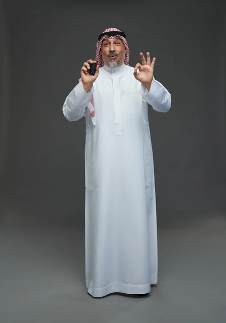 Saudi Man Holding Car Key with Okay Gesture in Studio