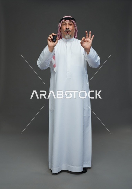 رجل سعودي بزي تقليدي يحمل مفتاح سيارة مع تعابير دهشة