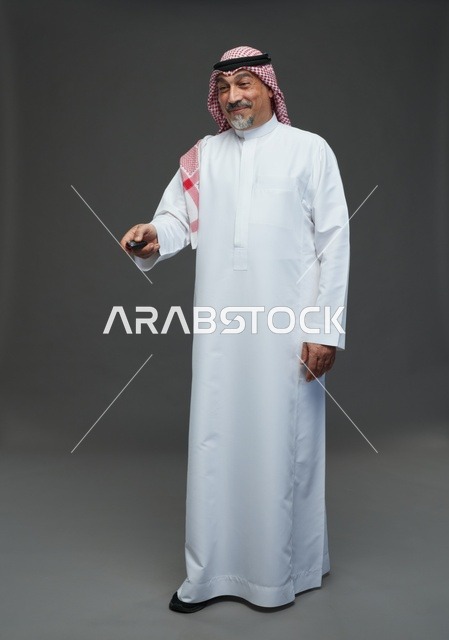 رجل سعودي بالزي التقليدي يحمل جهاز تحكم عن بعد