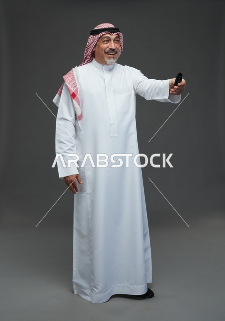 رجل عربي مسن يمسك مفتاح سيارة على خلفية رمادية