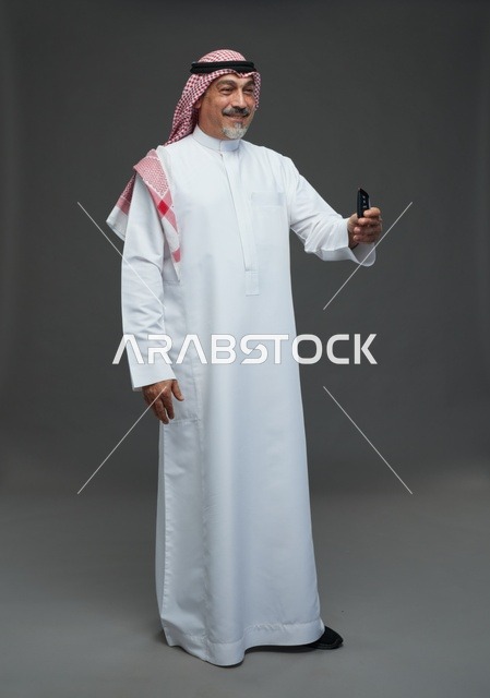 رجل سعودي مسن يحمل مفتاح سيارة في الاستوديو