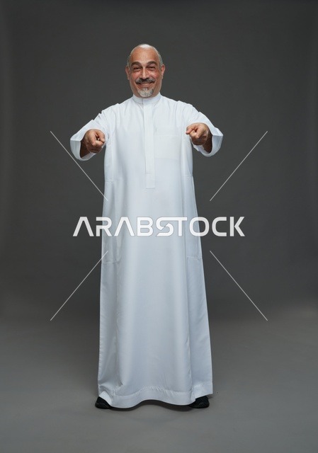 رجل سعودي مسن بالثوب الأبيض يشير بيديه في الاستوديو