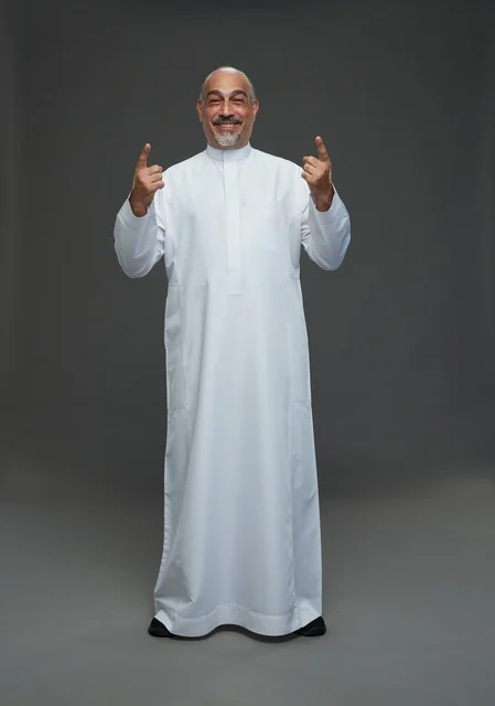 Smiling Saudi Man in White Thobe Pointing Upwards