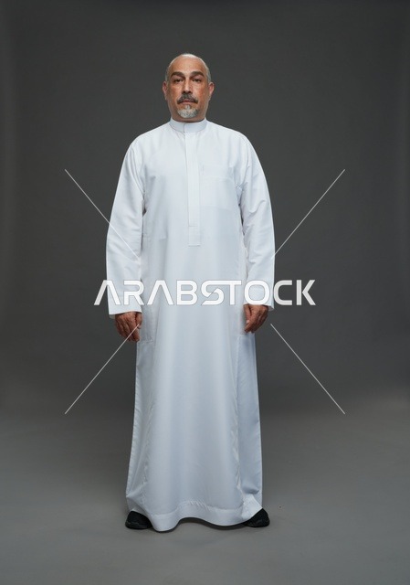 رجل عربي يرتدي الثوب الأبيض التقليدي في استوديو تصوير