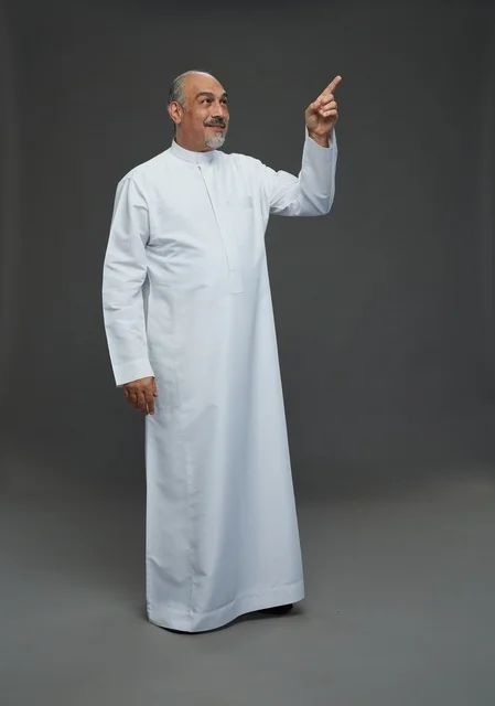 رجل عربي مسن بالثوب الأبيض يشير للأعلى بالاستوديو