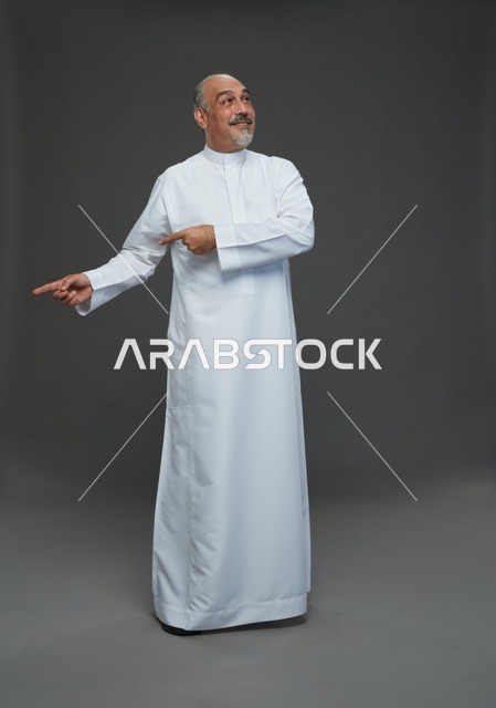 رجل سعودي بالثوب الأبيض التقليدي يشير إلى الجانب