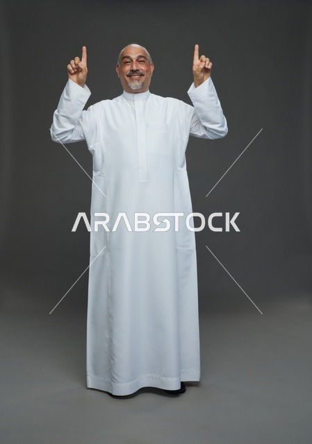 رجل عربي يرتدي الثوب الأبيض يشير للأعلى في الاستوديو