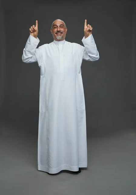 رجل عربي يرتدي الثوب الأبيض يشير للأعلى في الاستوديو