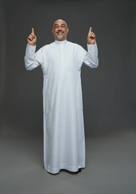 رجل سعودي بالثوب يشير للأعلى بخلفية رمادية