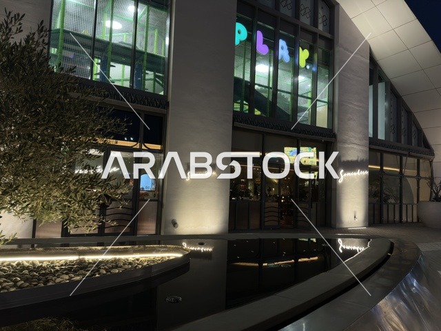 واجهة مبنى تجاري حديث ليلاً مع انعكاسات مائية