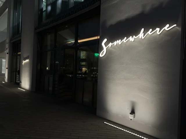 Somewhere Restaurant Neon Sign on Modern Night Building