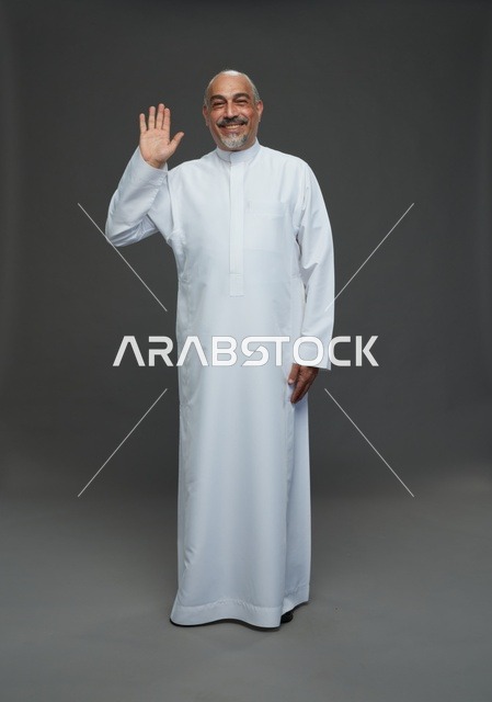 رجل عربي مسن يرتدي الثوب الأبيض يلوح بالتحية