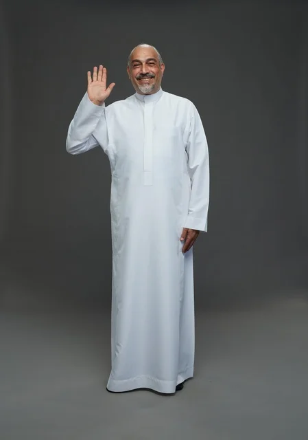 رجل عربي مسن يرتدي الثوب الأبيض يلوح بالتحية