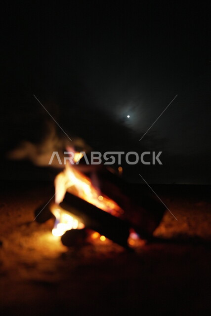 صورة لشعلة الحطب، حرق خشب الشجر، رحلات برية، أجواء شتوية، رحلة برية في صحراء المملكة العربية السعودية، جلسة بر عربية شعبية مع شعلة الحطب في صحراء السعودية، شبة نار، جمال القمر في سماء السعودية