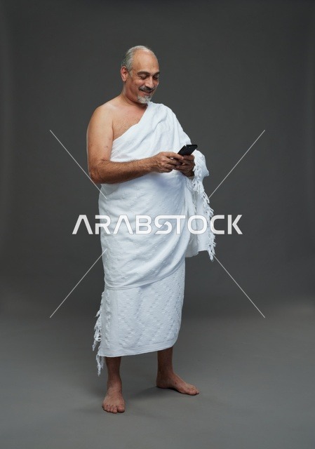 رجل سعودي بملابس الإحرام يستخدم الجوال في استوديو