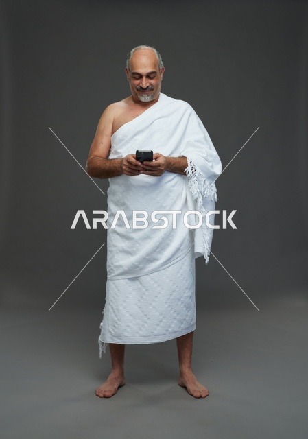 Arab Man in Ihram Using Smartphone Studio Background