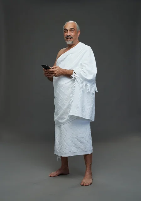 رجل عربي بملابس الإحرام يحمل هاتف ذكي في الاستوديو
