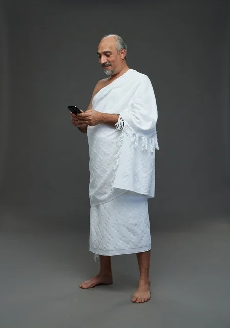 رجل عربي بملابس الإحرام يستخدم الجوال في الاستوديو