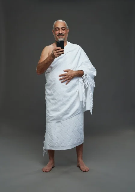رجل سعودي بملابس الإحرام يستخدم الهاتف الذكي في استوديو