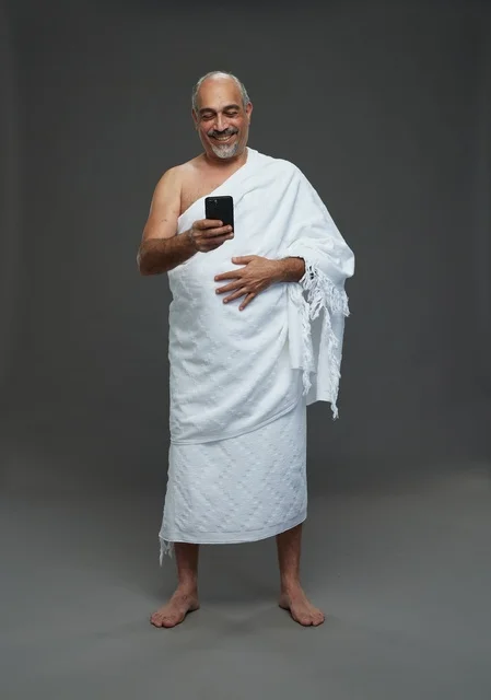 Smiling Arab Man in White Ihram Clothing Using Smartphone