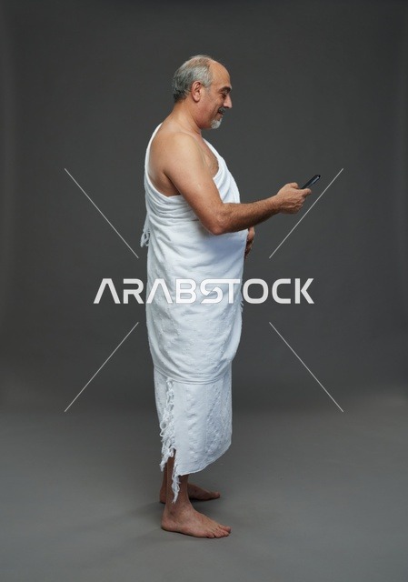 Saudi Pilgrim in Ihram Using Smartphone Studio Shot