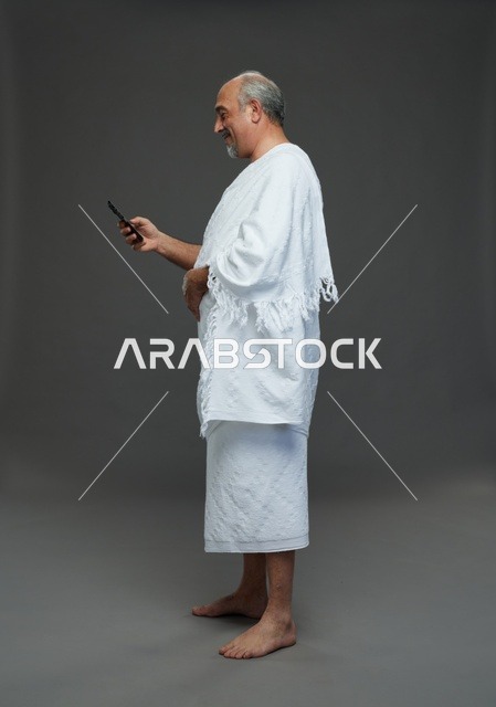 Saudi Pilgrim in Ihram Using Smartphone Studio Shot