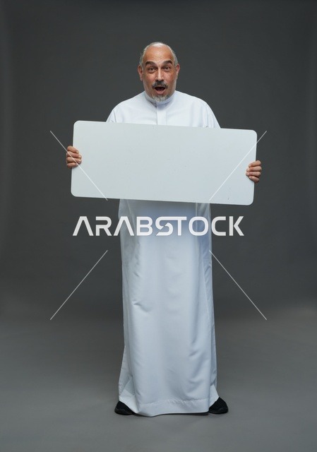 رجل سعودي يحمل لوحة بيضاء فارغة بتعبير مندهش