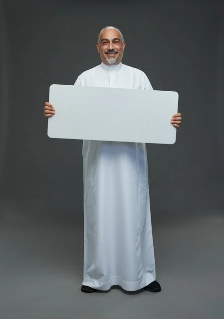 رجل سعودي يحمل لوحة بيضاء فارغة في الاستوديو