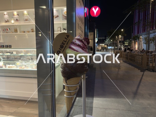 مجسم آيس كريم ضخم خارج واجهة متجر جيلاتو في الليل