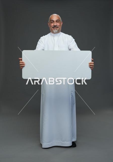 رجل سعودي بالثوب يحمل لوحة إعلانية فارغة
