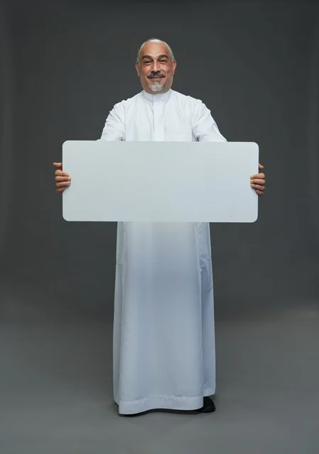 رجل سعودي بالثوب يحمل لوحة إعلانية فارغة