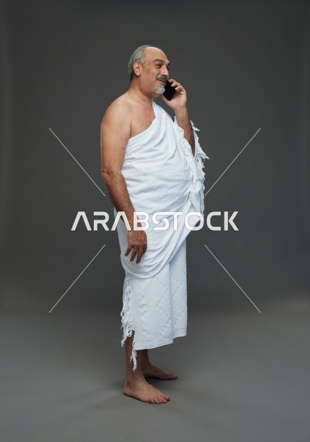 رجل سعودي بملابس الإحرام يتحدث بالجوال في الاستوديو