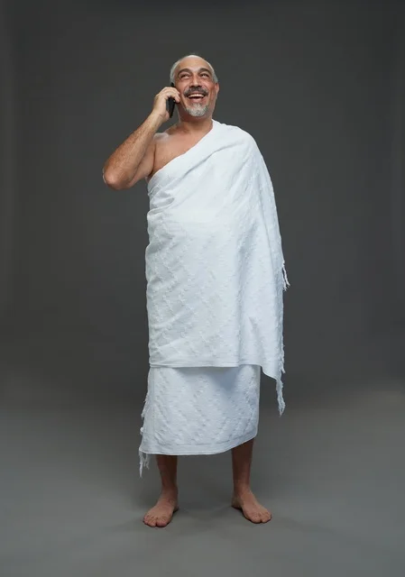 Saudi Man in Ihram Clothing Using Smartphone
